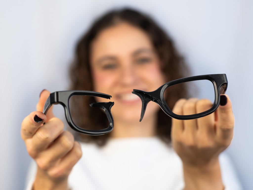 Foto einer jungen Frau, die eine zerbrochenes Brillengestell in die Kamera hält